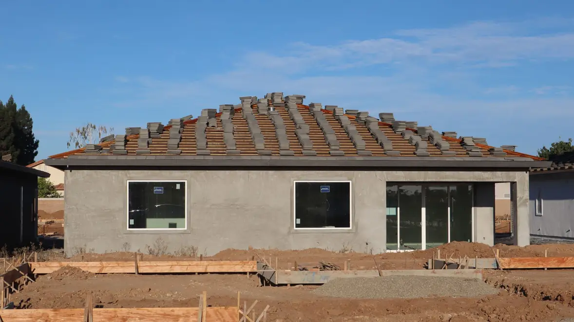 Maison en construction, tuiles réparties sur la charpente avant pose
