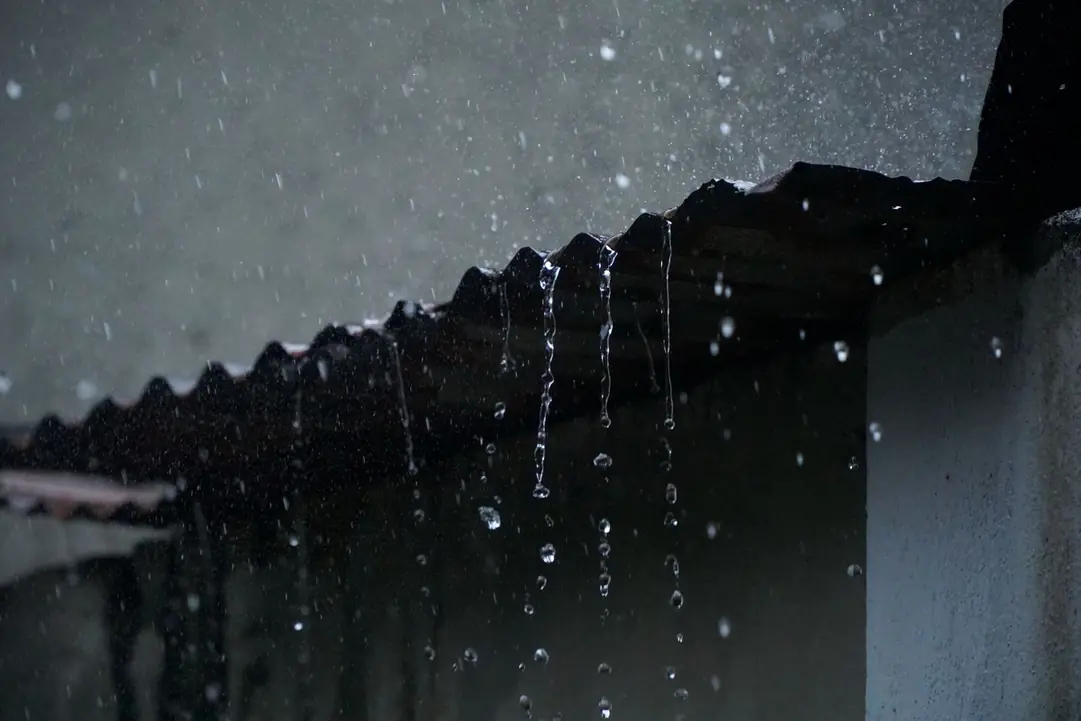 Eau de pluie ruisselant depuis le bord d'une toiture, la nuit