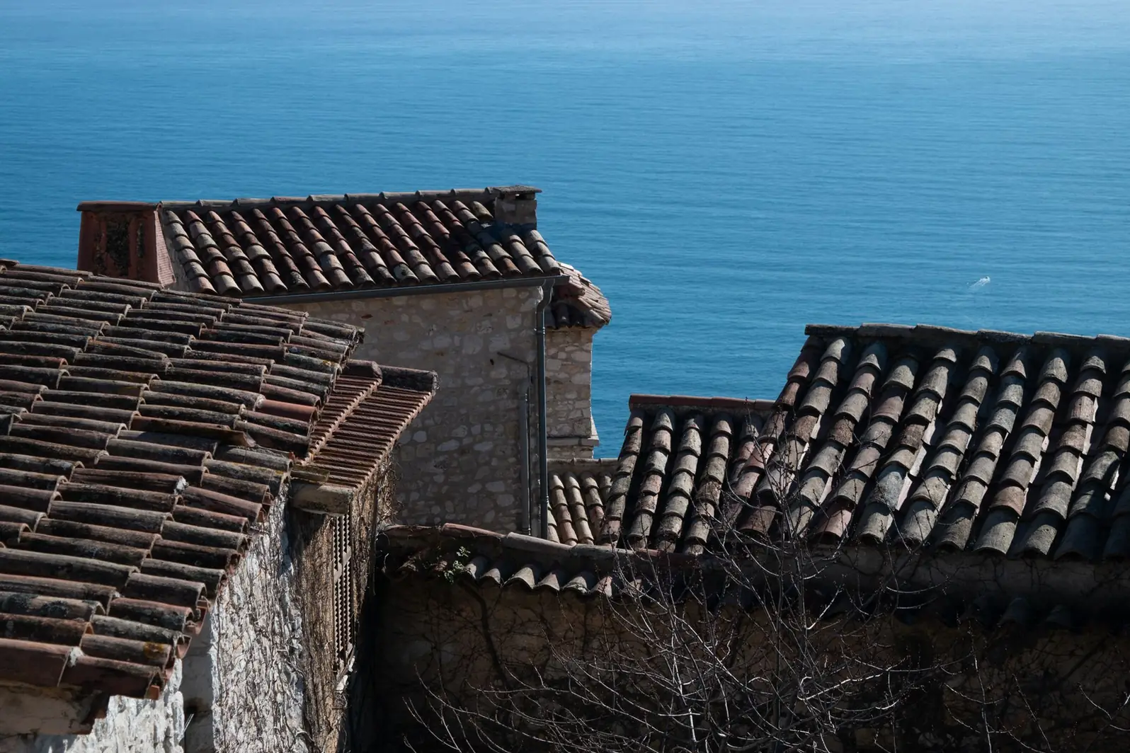 Toiture en tuile canal d'une maison de pierre dominant la mer